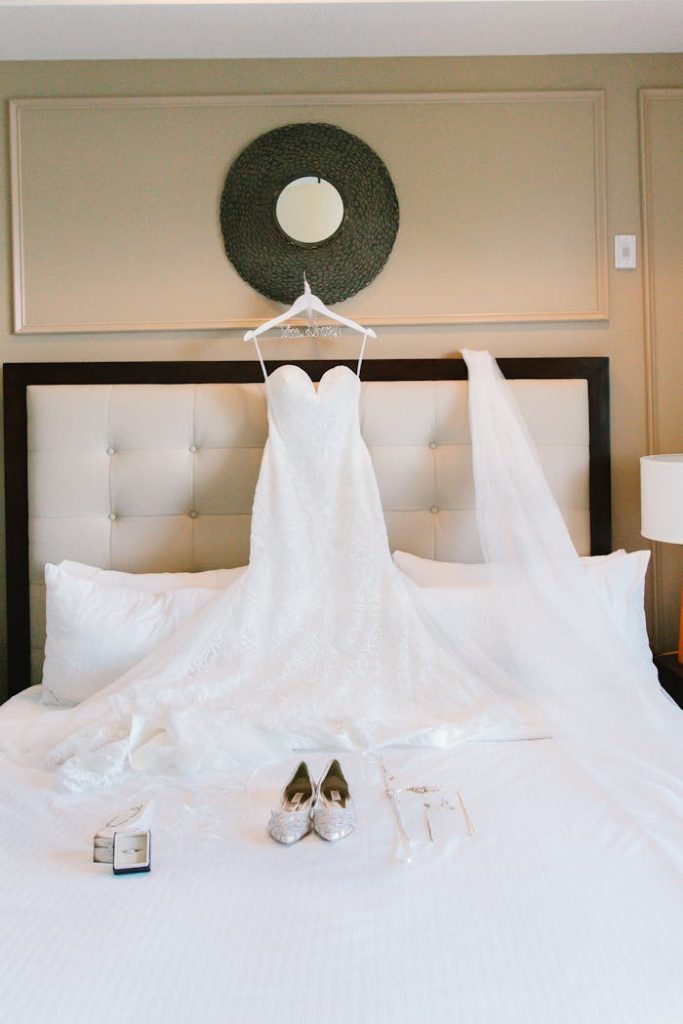 evènementiel Beautiful lace wedding dress on bed with stylish shoes, ready for a special day.