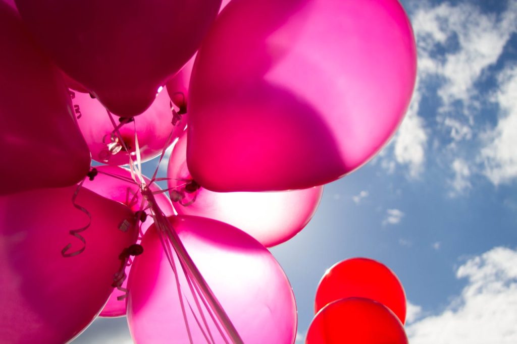 marketing Vibrant pink balloons float against a sunny blue sky, perfect for celebratory themes.